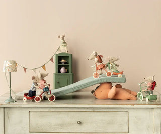 Souris grande soeur avec son tricycle maileg coton en herbe dans chambre enfants