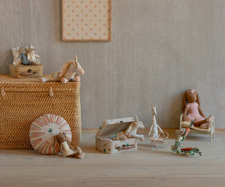 mise en scène avec jouets maileg : licorne, poupées, accessoires et meubles en bois, coton en herbe